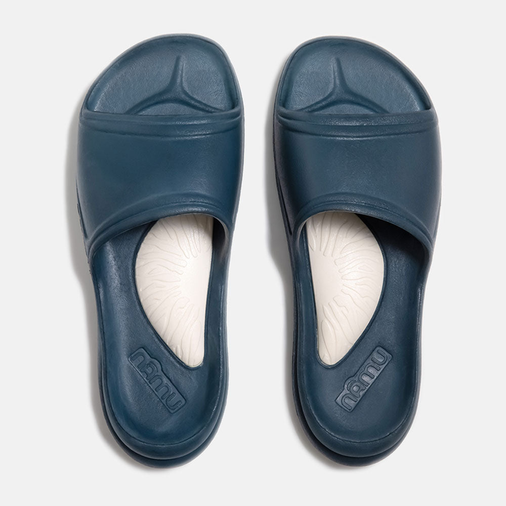 Pair of blue slides with white soles on a light gray background