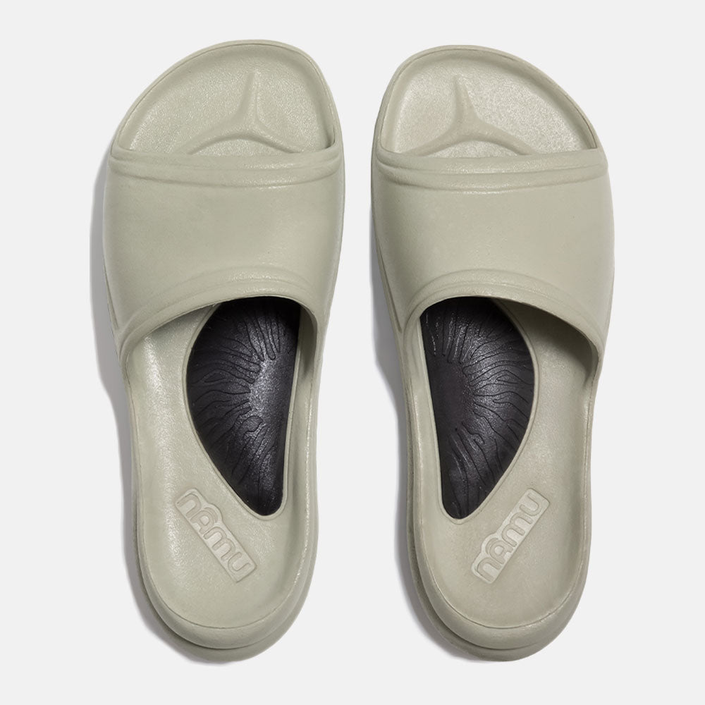 Pair of beige slides with black soles on a white background