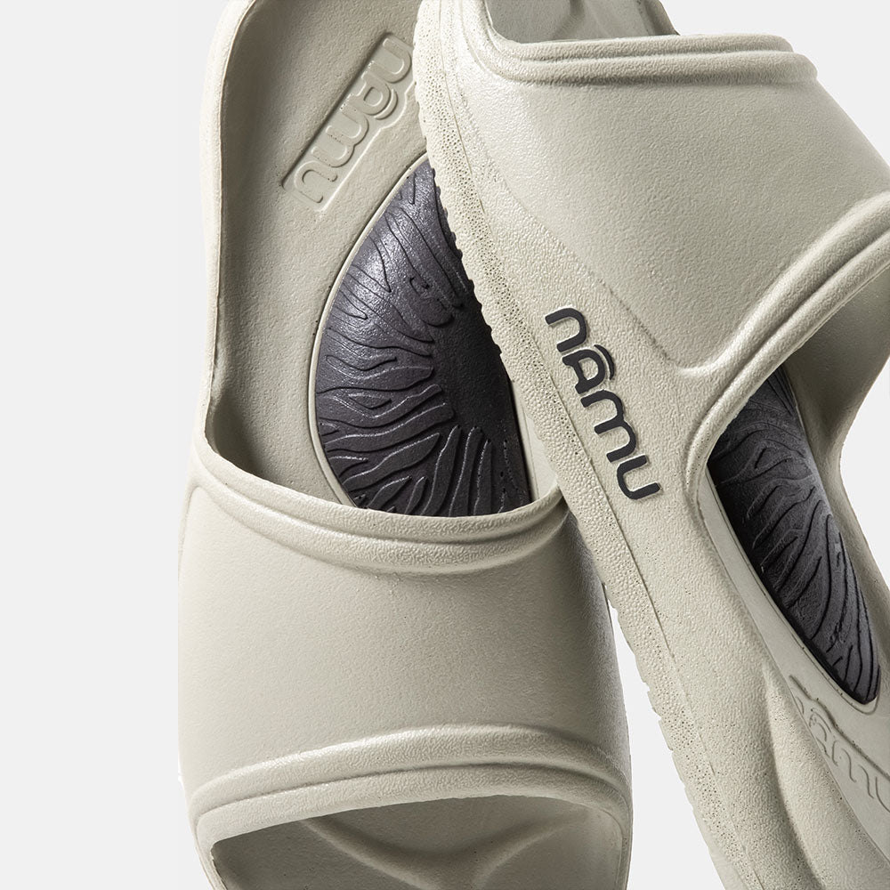 Close-up of beige sandals with 'nalu' branding on a light gray background