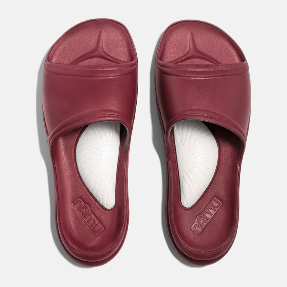 Pair of maroon slides with white soles on a light gray background