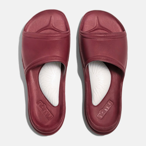 Pair of maroon slides with white soles on a light gray background