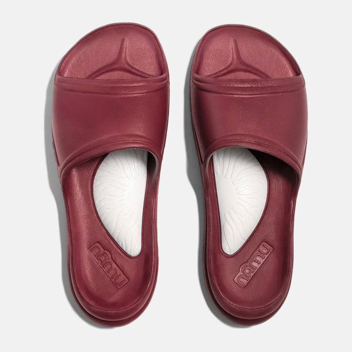 Pair of maroon slides with white soles on a light gray background