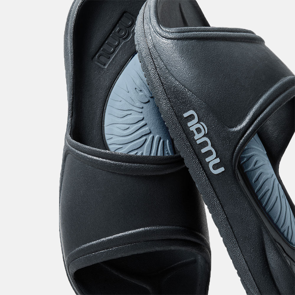 Black sandals with 'Namu' branding on a light gray background